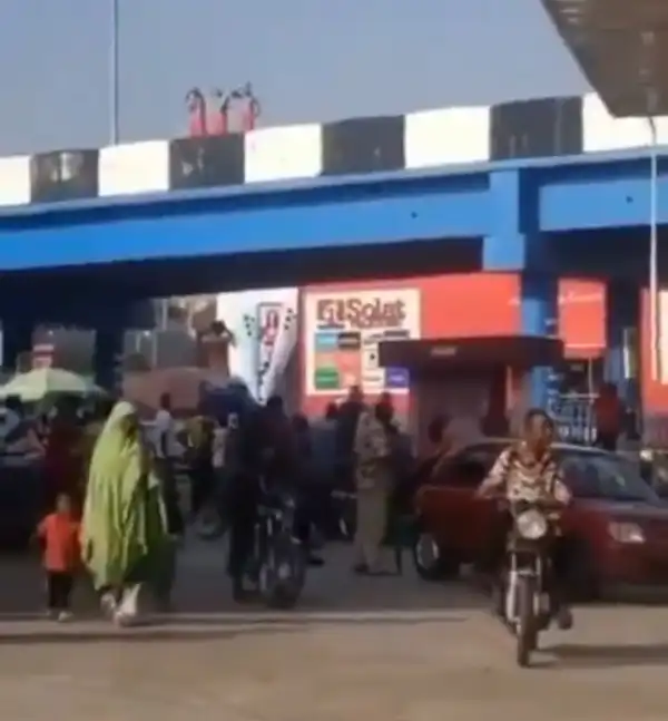 Crowd gather to watch 3 people clad in only red wrapper bathing on a bridge in Ibadan (video)